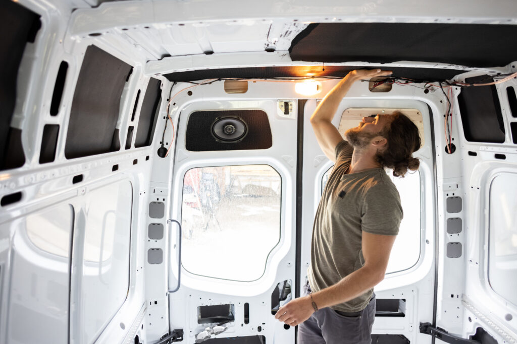 Man attaching thermal insulation in a camper van